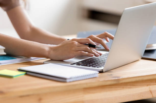 Person typing code on a laptop with notes beside them, illustrating mobile app backend development work.